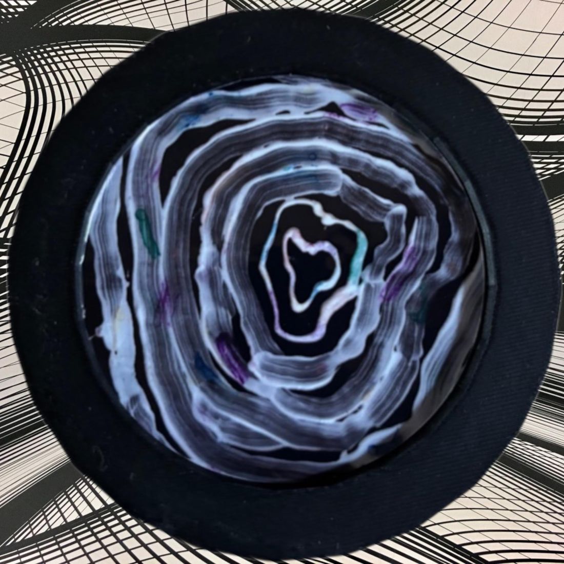 A round coaster printed with an expressive painting of migraine auras